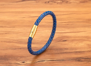 Dettaglio macro del bracciale in pelle intrecciata blu con chiusura dorata lucida