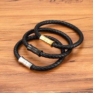 Three braided leather bracelets for men with silver gold and black magnetic clasps on wood