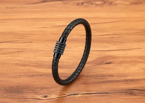 Dettaglio di bracciale in pelle intrecciata nera con chiusura magnetica in metallo