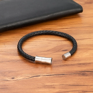 Men's black braided leather bracelet with magnetic stainless steel clasp on a wood table