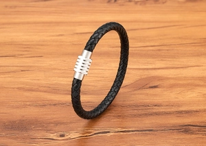 Dettaglio di un bracciale in pelle intrecciata nera con chiusura magnetica industriale argento