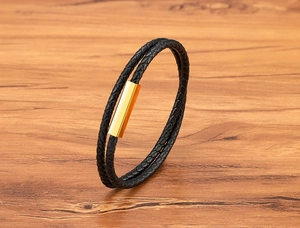 Macro shot of double-layered black woven leather bracelet with polished gold magnetic clasp