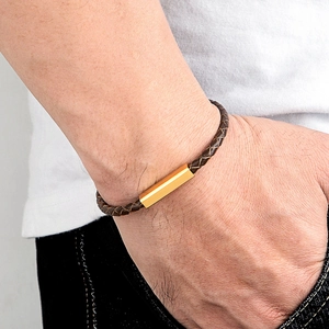 Men's brown braided leather bracelet with a gold rectangular metal charm on wrist