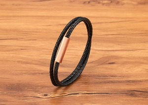 Detailed close-up of double-layer black braided leather bracelet with rose gold magnetic clasp