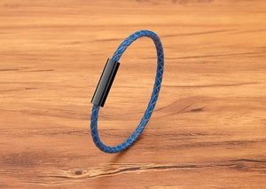 Close-up of blue braided leather bracelet with a sleek black magnetic steel clasp on wood