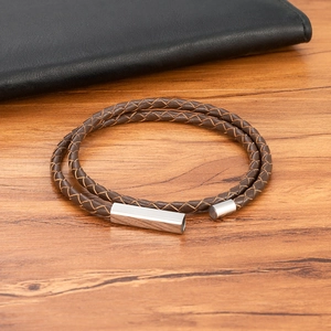 Men's double-wrap braided brown leather bracelet with silver magnetic buckle on wood
