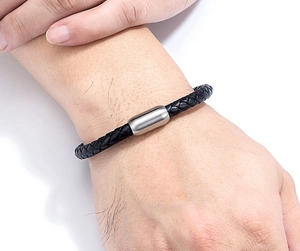 Détail d'un bracelet en cuir tressé noir avec fermoir magnétique en acier inoxydable brossé