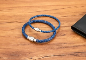 Détail de bracelets en cuir tressé bleu avec fermoirs magnétiques en acier cylindriques