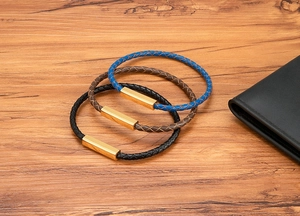 Close-up of three braided leather bracelets in blue, brown, and black with gold clasps