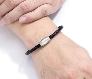 Nahaufnahme von geflochtenem schwarzen Lederarmband mit poliertem Magnetverschluss