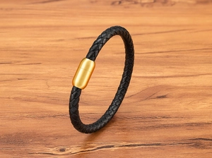 Gros plan d'un bracelet en cuir tressé noir avec un fermoir magnétique doré poli