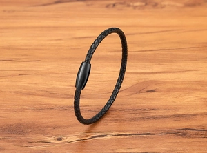 Detail eines schwarzen geflochtenen Lederarmbands mit mattem schwarzem Magnetverschluss