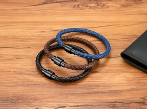 Gros plan de bracelets en cuir tressé bleu, marron et noir avec fermoirs magnétiques noirs
