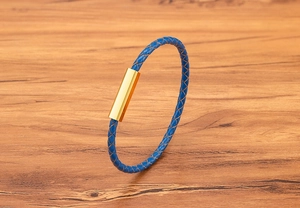 Detail of blue braided leather bracelet with a polished gold magnetic stainless steel clasp