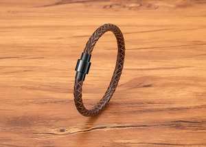 Détail macro du bracelet en cuir tressé marron avec fermoir magnétique en acier noir