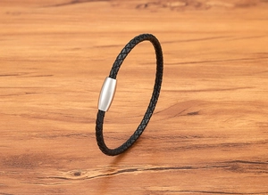 Nahaufnahme eines schwarzen Lederarmbands mit silbernem Magnetverschluss auf Holz