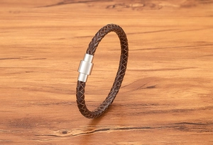 Gros plan sur un bracelet en cuir tressé marron foncé avec fermoir magnétique en acier