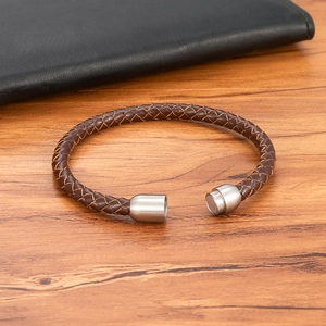 Geflochtenes braunes Lederarmband mit gebürstetem Edelstahl-Magnetverschluss auf Holz