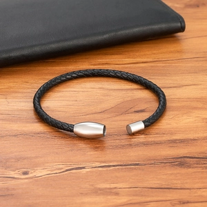 Braided black leather bracelet for men with silver stainless steel magnetic clasp on wood