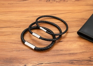 Macro view of black braided leather bracelets with polished silver magnetic clasps