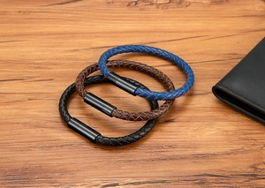 Detail of blue, brown and black braided leather bracelets with black magnetic clasps