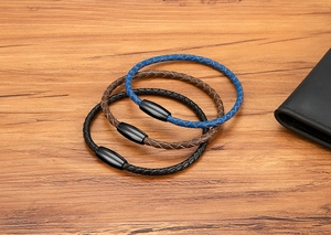 Close-up of three woven leather bracelets in blue, brown, and black with magnetic clasps