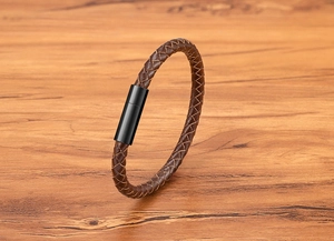 Close-up of brown braided leather bracelet with black magnetic clasp on wood