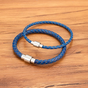 Bracelets en cuir tressé bleu avec fermoir magnétique en acier sur fond bois