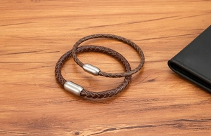 Detail von zwei dunkelbraunen geflochtenen Lederarmbändern mit mattem Silbermagnetverschluss