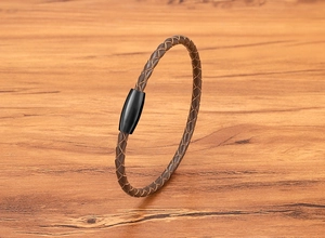 Detail view of brown braided leather bracelet with a sleek black magnetic steel clasp