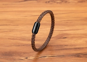 Nahaufnahme von braunem Lederarmband mit schwarzem Magnetverschluss auf Holz