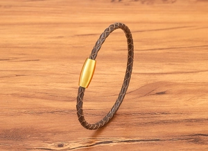 Macro detail of brown braided leather bracelet with golden magnetic stainless steel clasp