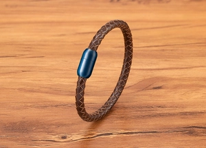 Detail des braun geflochtenen Lederarmbands mit einem zylindrischen blauen Magnetverschluss