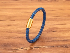 Detail eines blau geflochtenen Lederarmbands mit mattgoldener Magnetschließe aus Edelstahl