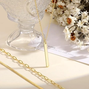 Detail view of layered gold necklace set with vertical bar pendant and snake chain