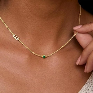 Gold layered satellite chain necklace featuring a green gemstone and letter E pendant
