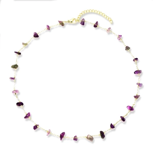 Golden necklace with irregular purple and green raw crystal stones on a white background