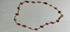Detailed shot of irregular red agate stones and white pearls on a gold chain necklace