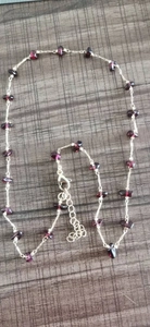Macro shot of irregular red crystal beads on a stainless steel chain with lobster clasp