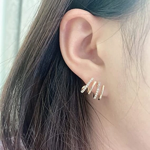 Detailed close-up of golden four-prong zircon cuff earrings worn on a model ear