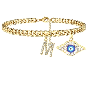 Makroaufnahme der goldenen Panzerkette mit Mikro-Pave-Buchstabe M und Evil-Eye-Anhänger