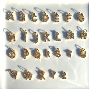 Set aus 26 vergoldeten Buchstaben-Anhängern mit lila Zirkon-Steinen und starken Schatten