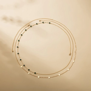 Chic layered gold body chain featuring emerald green stones and polished metal discs