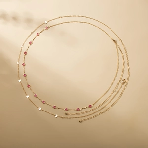 Detail view of double-layer gold chain with pink gemstones and sequins and lobster clasp