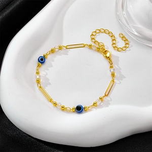 Goldenes Evil-Eye-Armband mit blauen Perlen und Kristallen auf weißem Keramiktablett