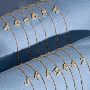 Vergoldete Buchstaben-Halskette mit Zirkonia-Besatz auf blauem Seidenstoff