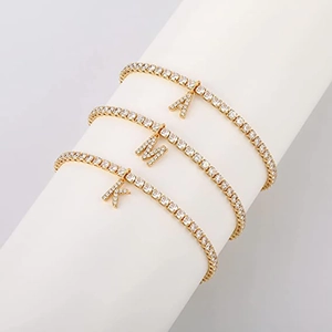 Detaillierte Ansicht von drei goldenen Strass-Tennisarmbändern mit Buchstaben-Anhängern A, M, K