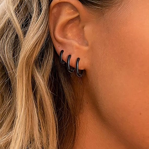 Drei minimalistische schwarze Punk 18k Gold Ohrringe getragen am Ohrläppchen Set