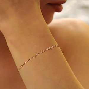 Nahaufnahme des minimalistischen 14K vergoldeten Wasserwellen-Armbands am Handgelenk