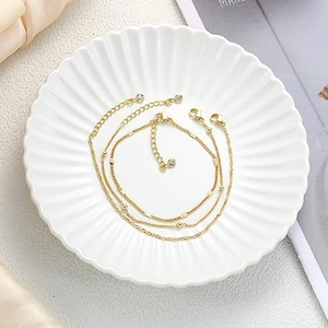 Dreiteiliges 14K vergoldetes mehrlagiges Armband-Set mit weißen Strasssteinen auf Teller